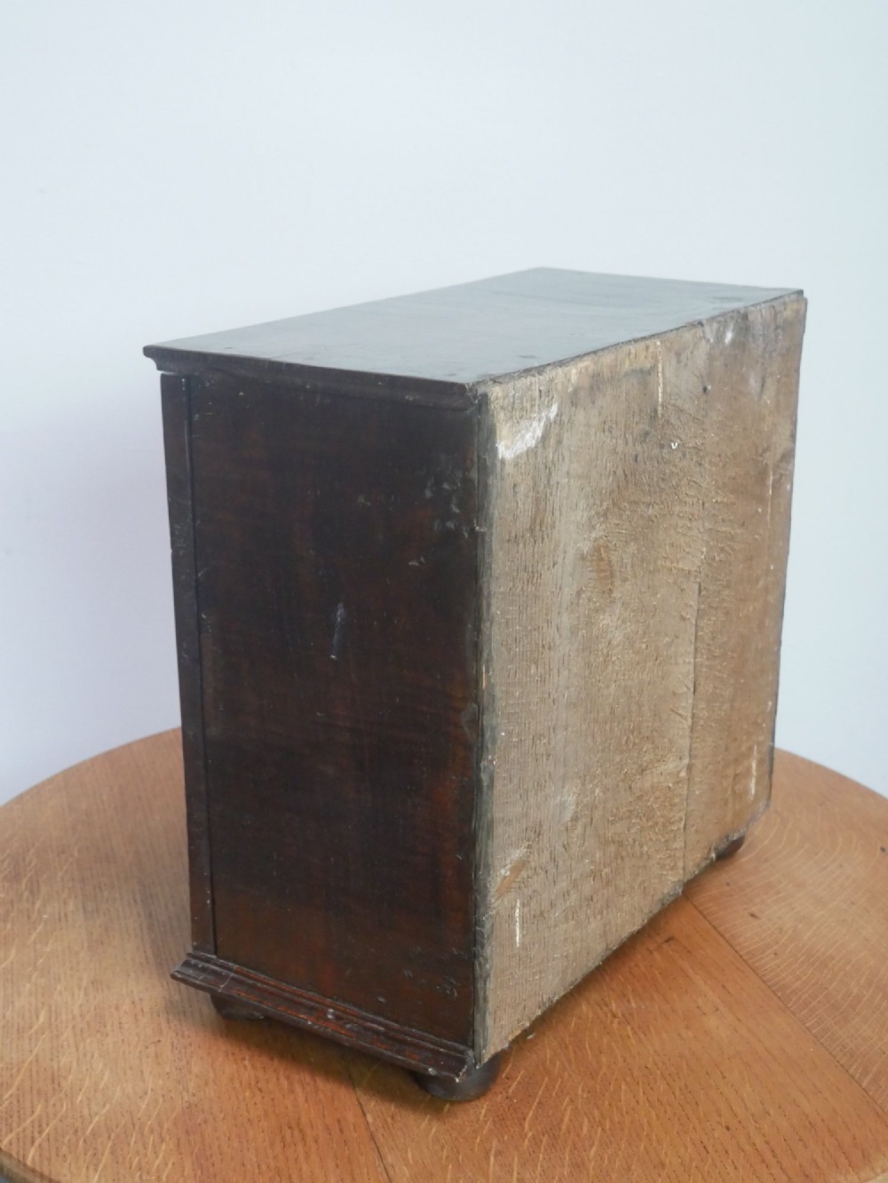 An 18th-century dark oak spice cupboard with a single fielded panel door, brass escutcheon, and bun feet. View VIII