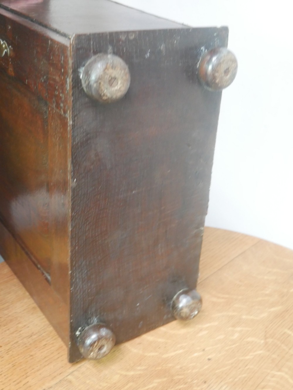 An 18th-century dark oak spice cupboard with a single fielded panel door, brass escutcheon, and bun feet. View X
