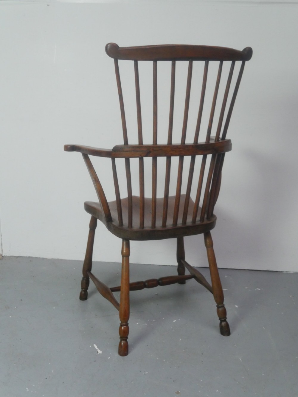 A mid-19th-century warm brown wooden Windsor armchair featuring a double-tier spindle back, carved saddle seat, curved armrests, and turned legs. View III