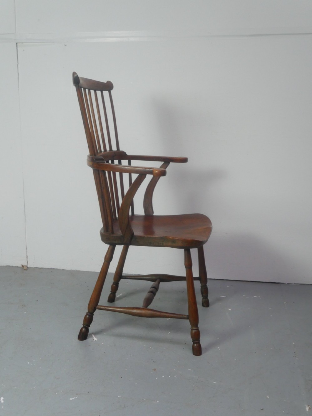 A mid-19th-century warm brown wooden Windsor armchair featuring a double-tier spindle back, carved saddle seat, curved armrests, and turned legs. View IV