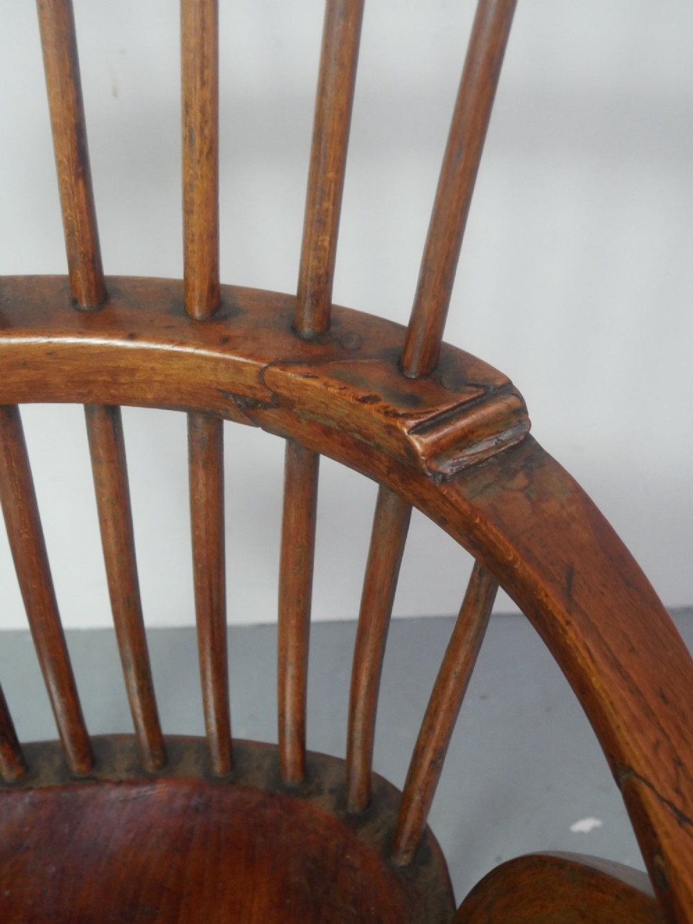 A mid-19th-century warm brown wooden Windsor armchair featuring a double-tier spindle back, carved saddle seat, curved armrests, and turned legs. View V