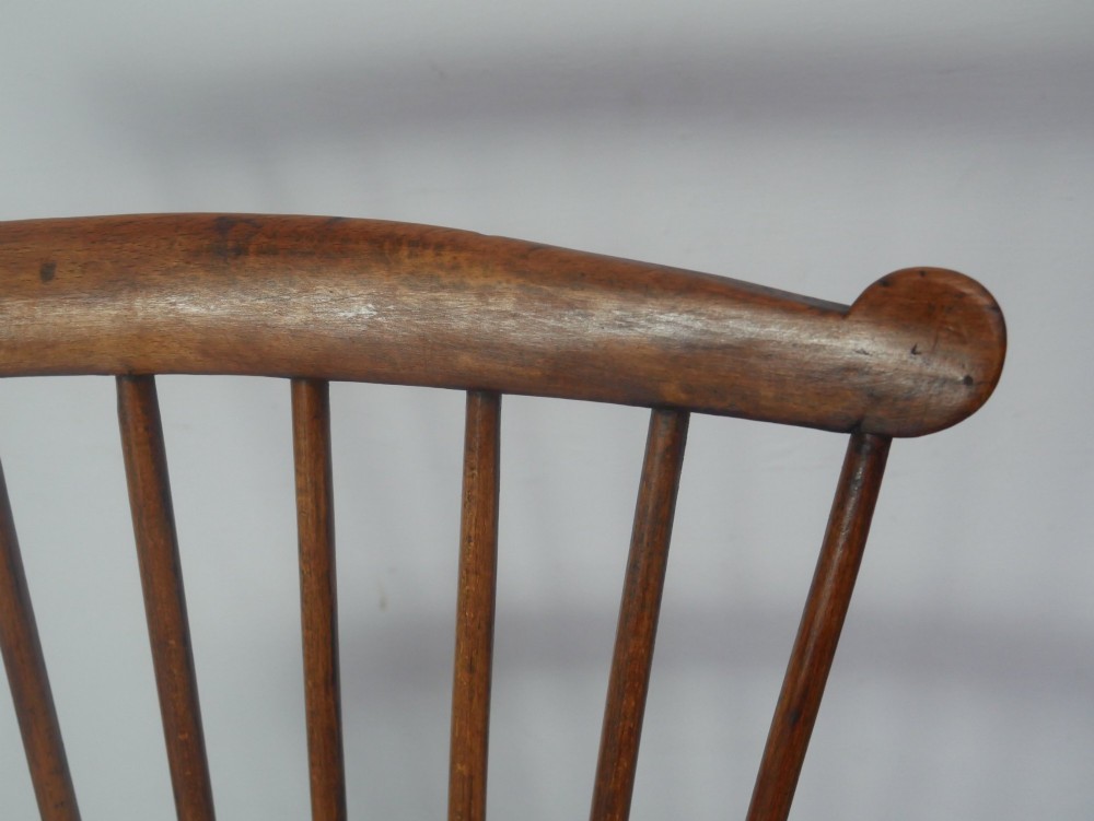 A mid-19th-century warm brown wooden Windsor armchair featuring a double-tier spindle back, carved saddle seat, curved armrests, and turned legs. View VII