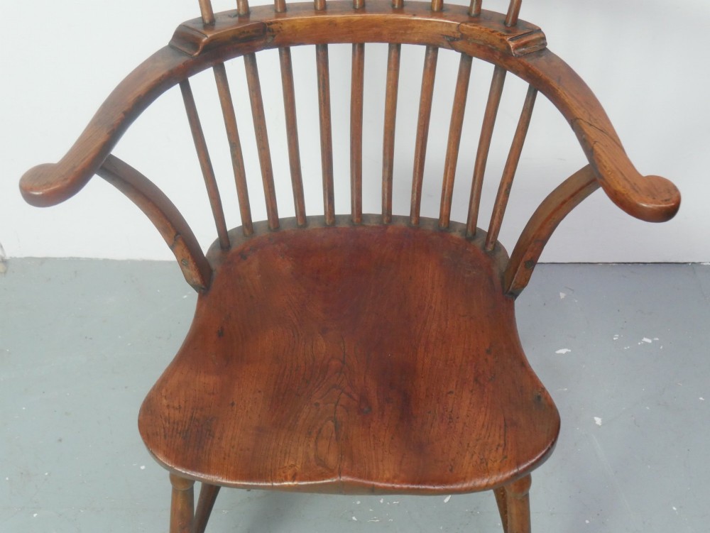 A mid-19th-century warm brown wooden Windsor armchair featuring a double-tier spindle back, carved saddle seat, curved armrests, and turned legs. View VIII