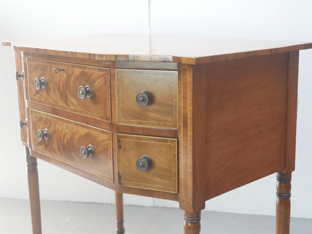 A small Regency mahogany side cabinet featuring flame mahogany drawer fronts, brass knob handles, inlaid borders, and slender turned legs. View II