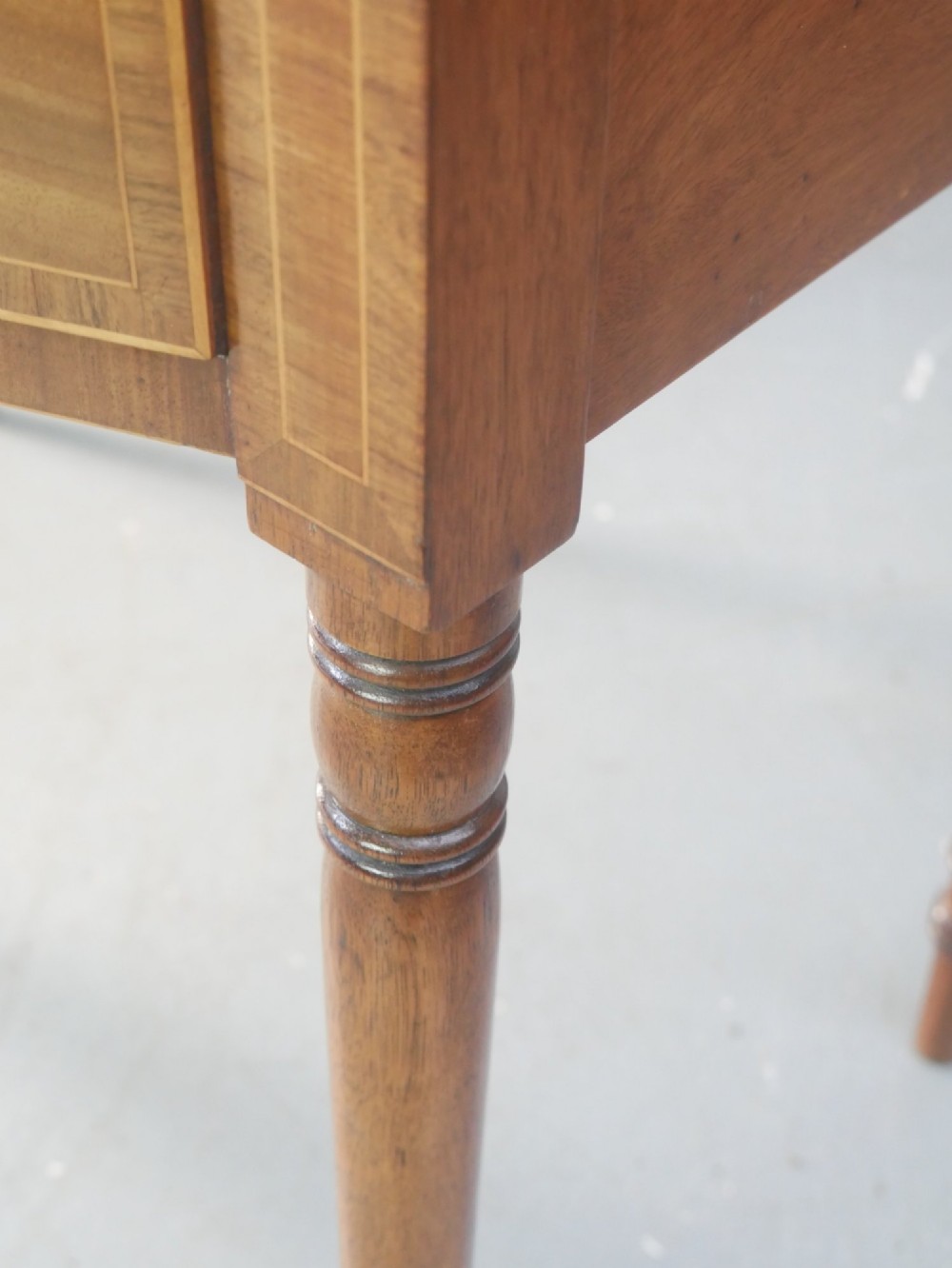 A small Regency mahogany side cabinet featuring flame mahogany drawer fronts, brass knob handles, inlaid borders, and slender turned legs. View III