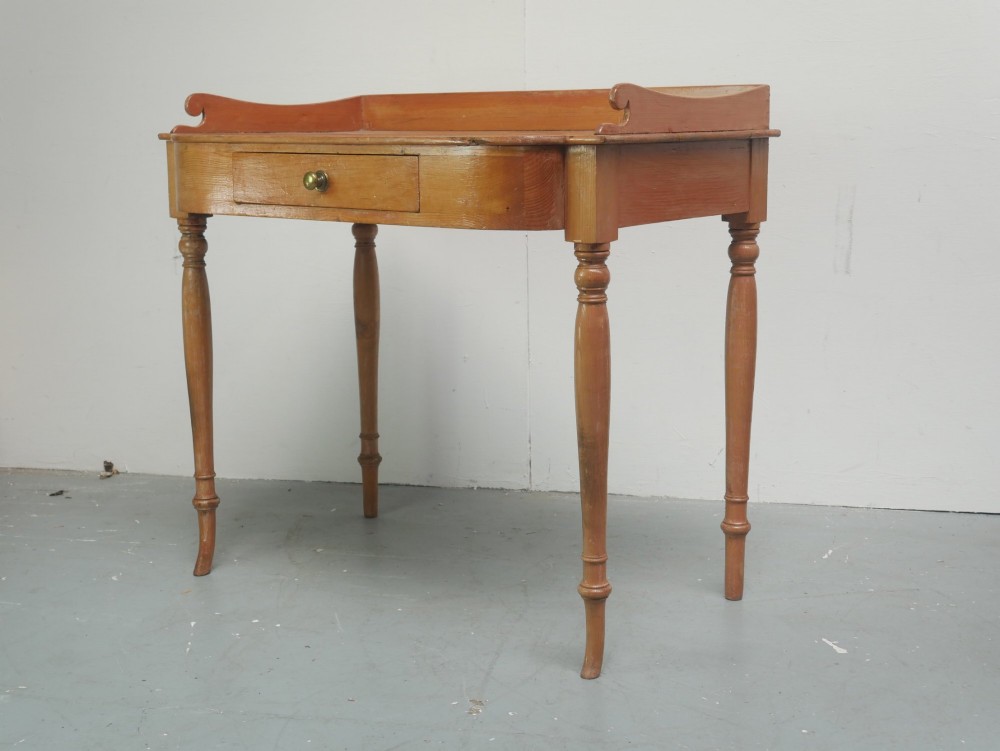 A Regency warm pine writing table featuring turned legs, a single central drawer with a brass knob, and a raised gallery upstand along the top. View II
