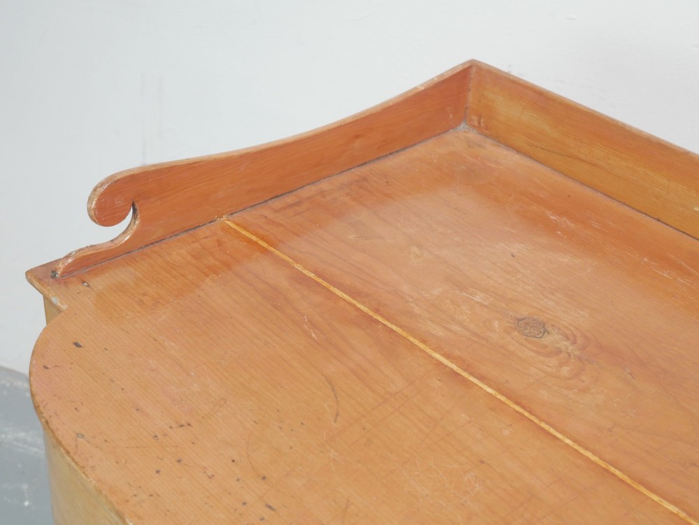 A Regency warm pine writing table featuring turned legs, a single central drawer with a brass knob, and a raised gallery upstand along the top. View V