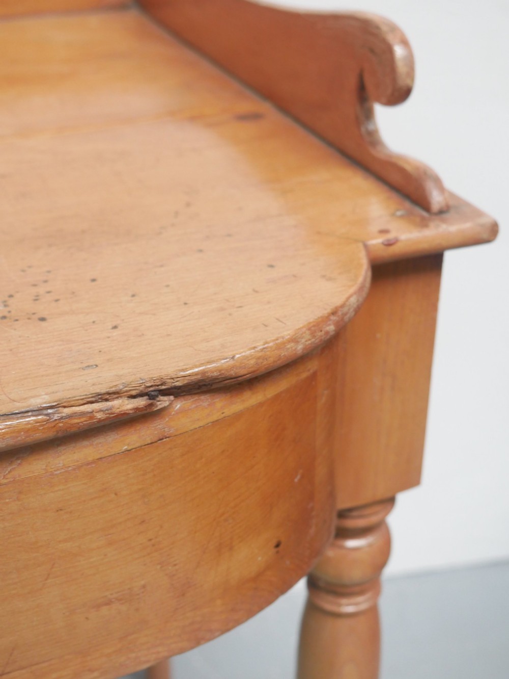 A Regency warm pine writing table featuring turned legs, a single central drawer with a brass knob, and a raised gallery upstand along the top. View XIII