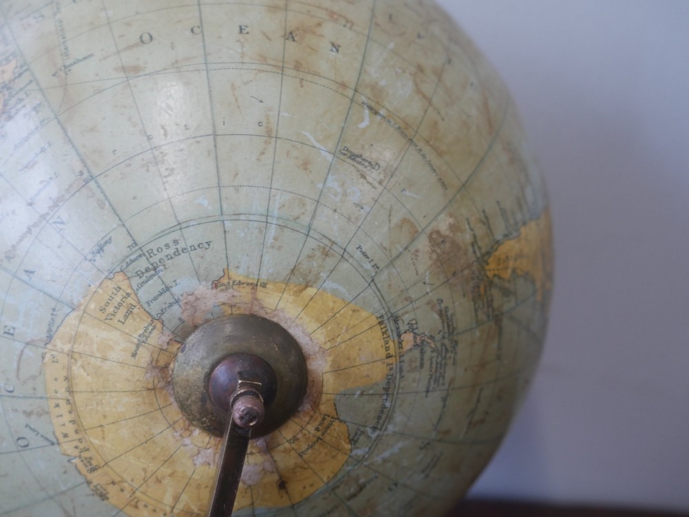 An antique terrestrial desk globe titled Philips British Empire Globe featuring cream paper gores mounted on a brass semi-meridian arm and an ebonised turned wooden base. View VI