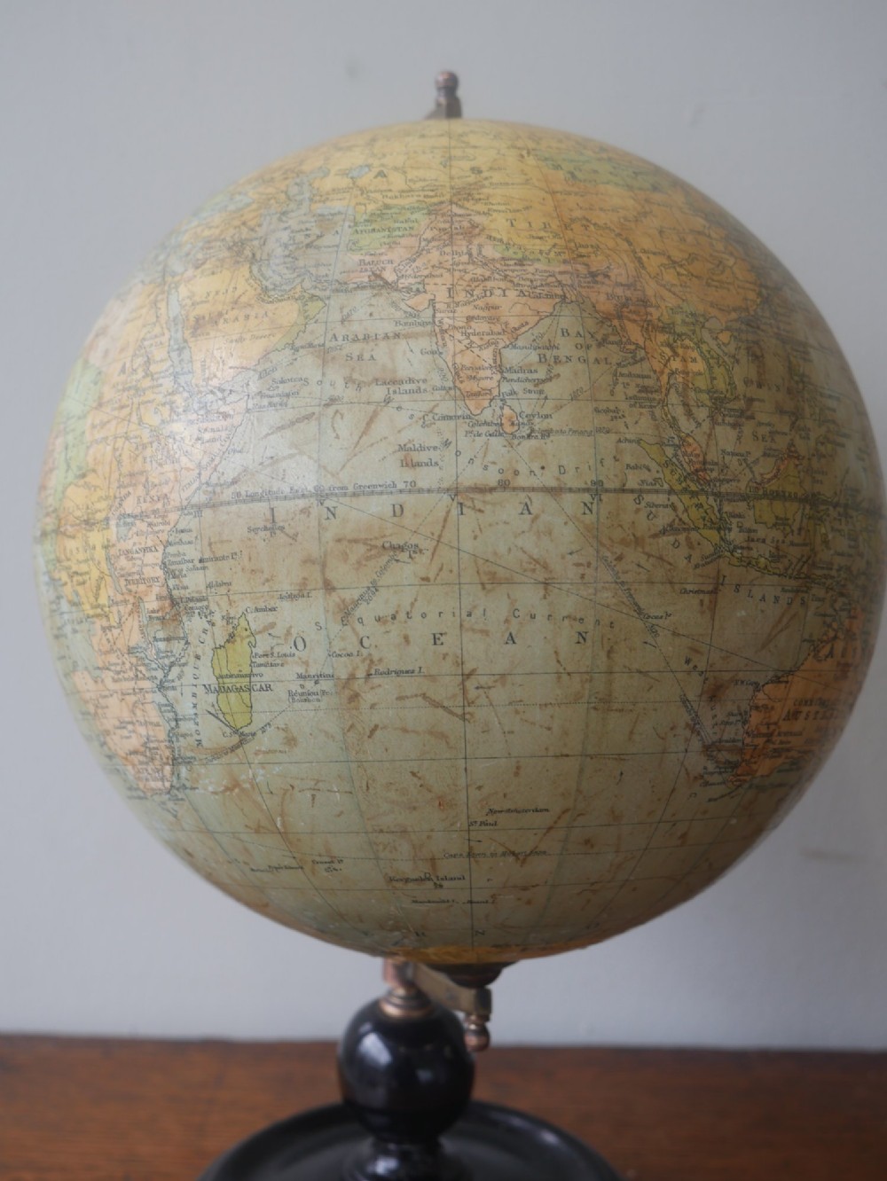 An antique terrestrial desk globe titled Philips British Empire Globe featuring cream paper gores mounted on a brass semi-meridian arm and an ebonised turned wooden base. View VII