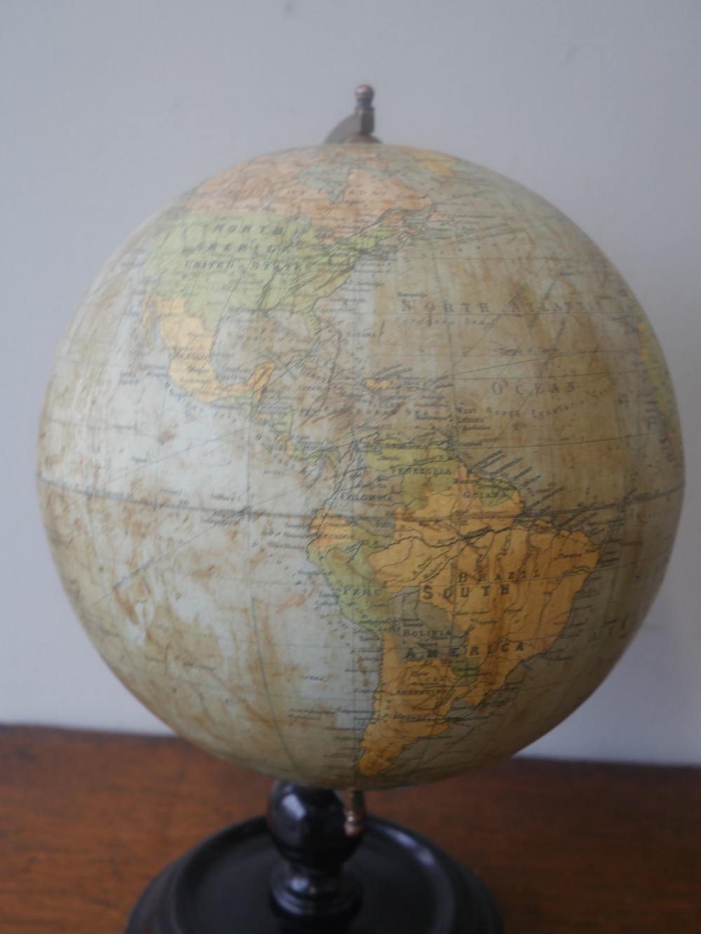 An antique terrestrial desk globe titled Philips British Empire Globe featuring cream paper gores mounted on a brass semi-meridian arm and an ebonised turned wooden base. View IX