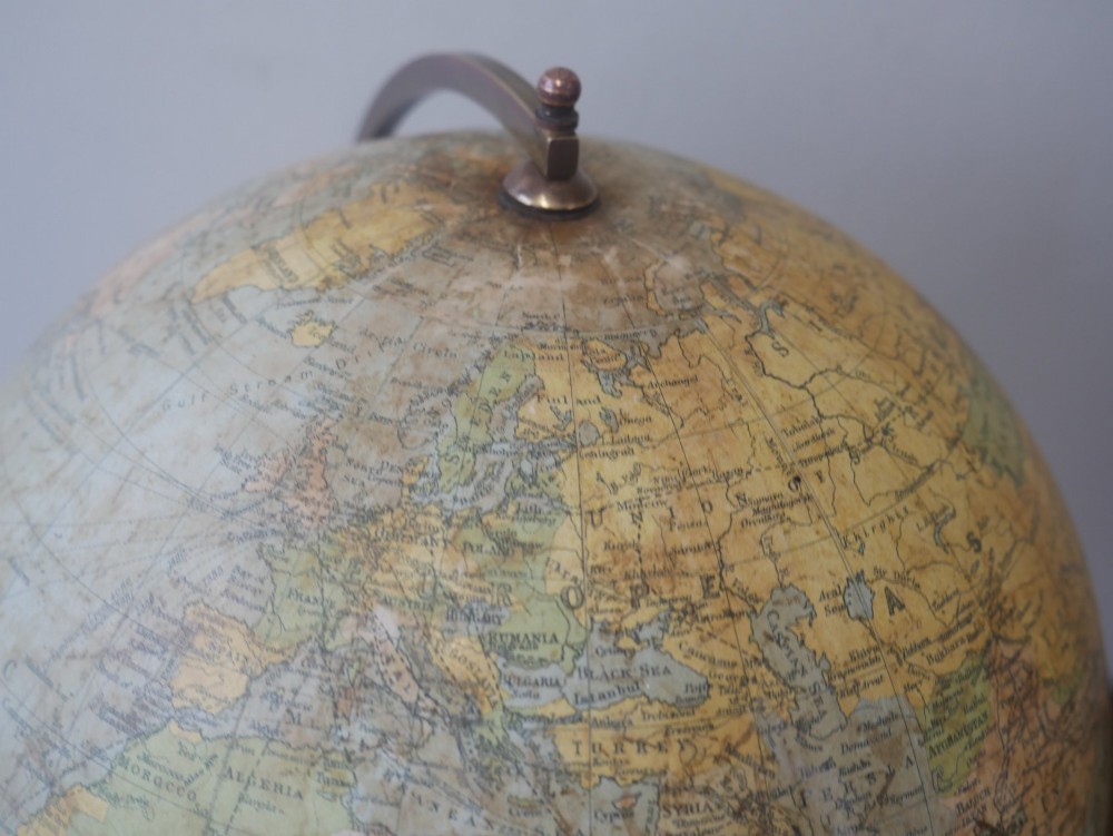An antique terrestrial desk globe titled Philips British Empire Globe featuring cream paper gores mounted on a brass semi-meridian arm and an ebonised turned wooden base. View X
