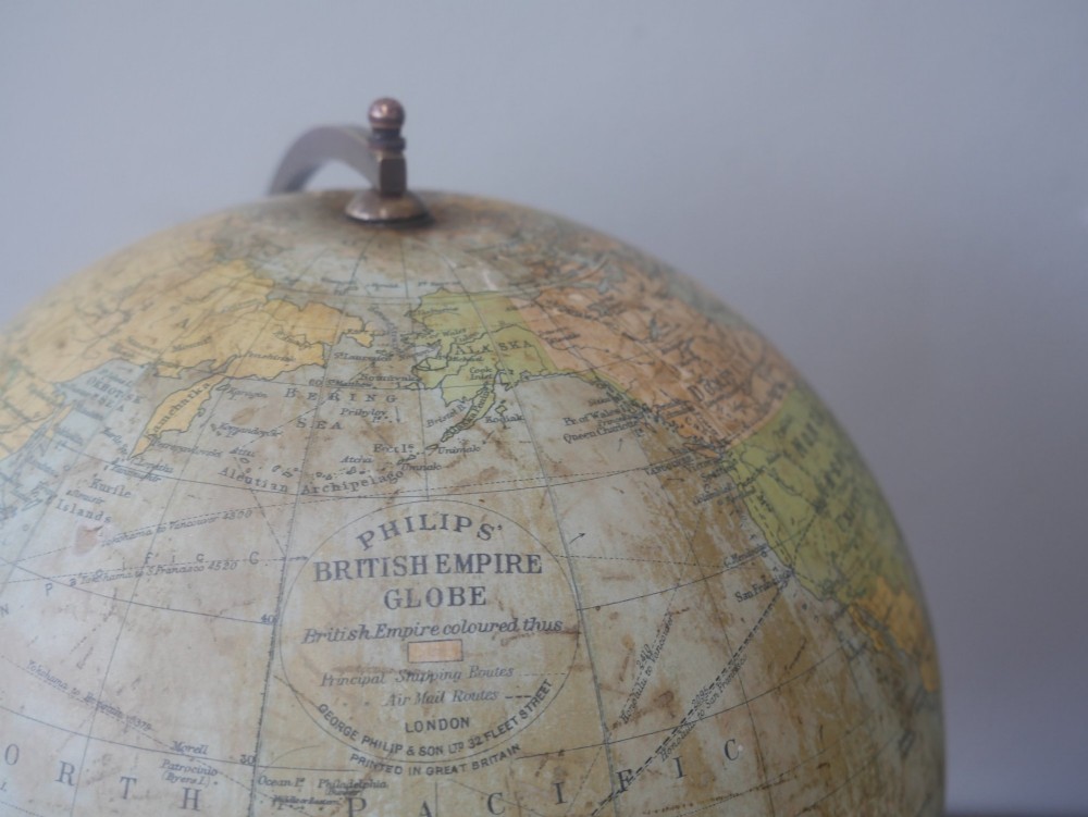 An antique terrestrial desk globe titled Philips British Empire Globe featuring cream paper gores mounted on a brass semi-meridian arm and an ebonised turned wooden base. View XI