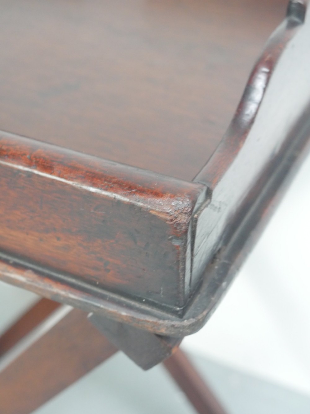 A dark mahogany butlers tray with integrated hand cutout handles resting on a matching folding x-frame stand. View IV