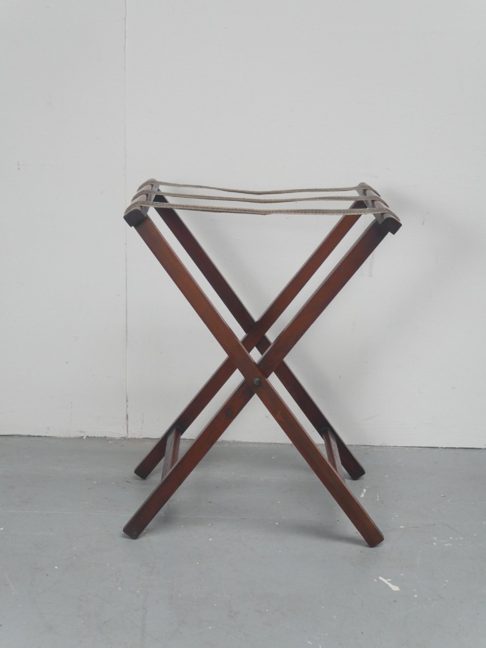 A dark mahogany butlers tray with integrated hand cutout handles resting on a matching folding x-frame stand. View IX