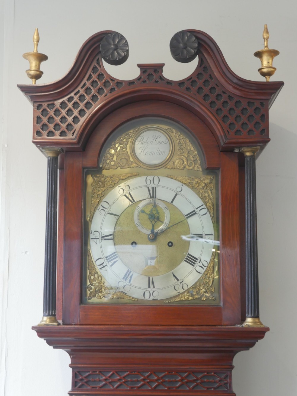 A tall Scottish mahogany longcase clock featuring a swan-neck pediment with brass finials, fretwork details, and an brass dial with silvered chapter ring. View II