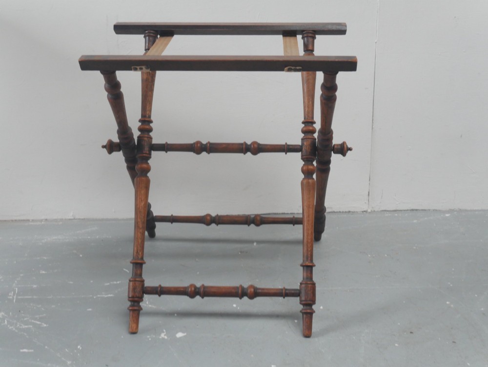 A dark oak butler tray with gallery edges and cut-out handles resting atop a matching wooden folding X-frame stand with turned legs. View VIII