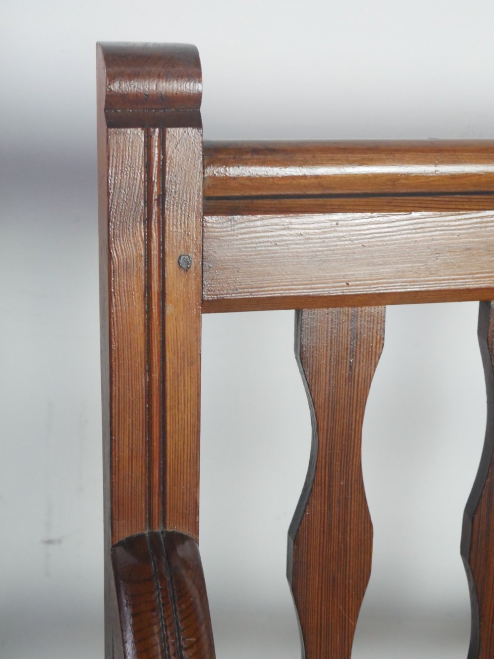 A warm brown pine hall bench featuring turned front legs, shaped back slats, swept armrests, and a solid timber seat. View II