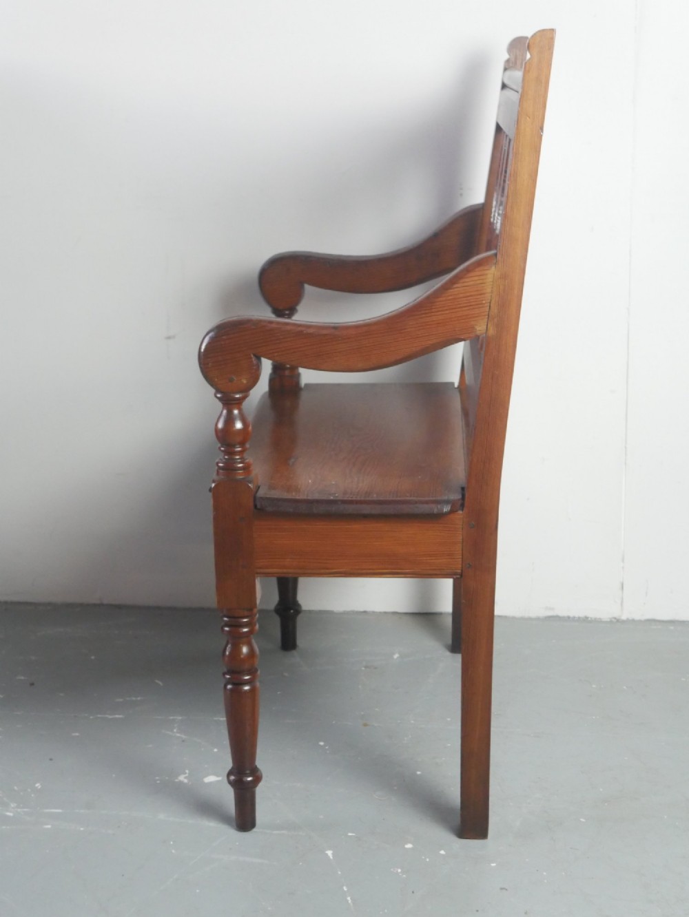 A warm brown pine hall bench featuring turned front legs, shaped back slats, swept armrests, and a solid timber seat. View V