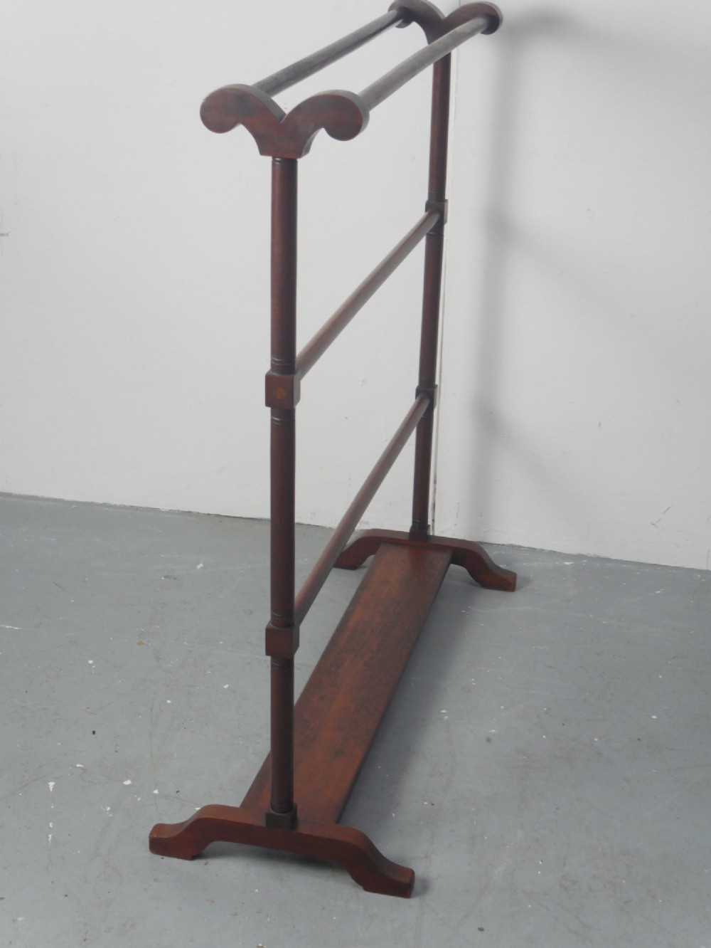 A dark mahogany freestanding towel rail featuring scrolled top terminals, turned vertical posts, and multiple horizontal drying bars supported on sledge feet. View IV