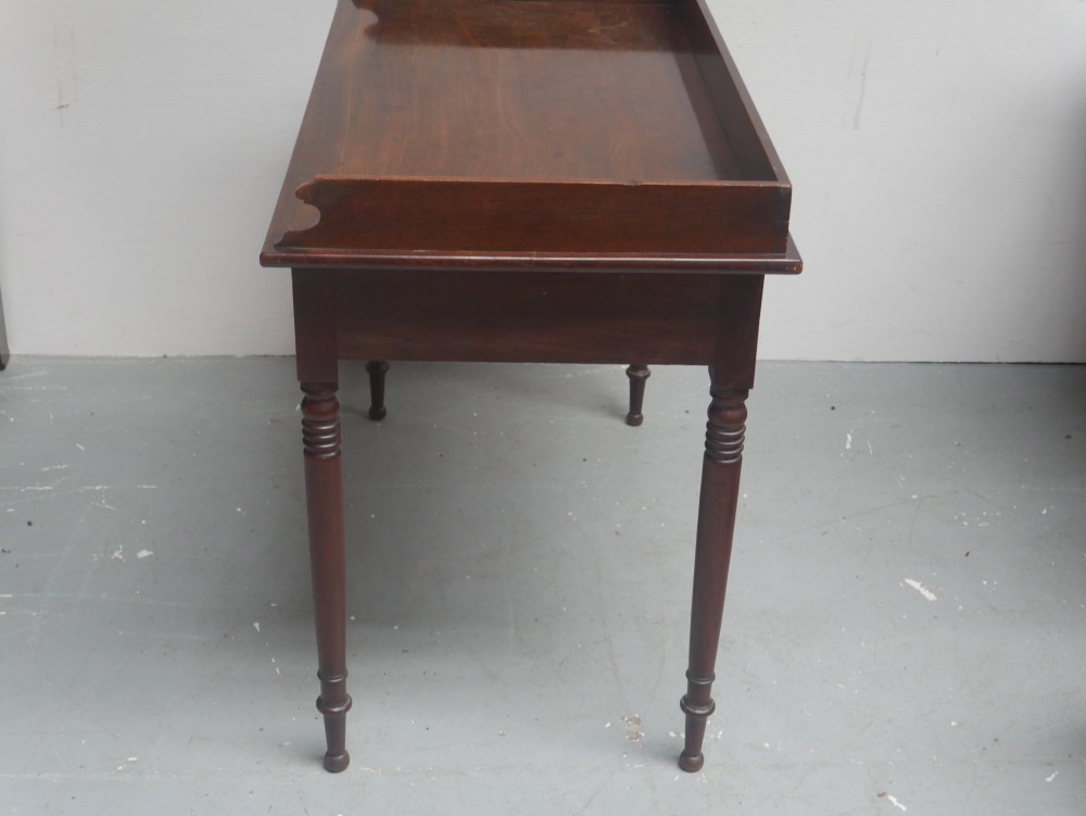 An antique Regency mahogany writing table featuring a raised gallery back, two frieze drawers with line inlay, and turned legs. View IX