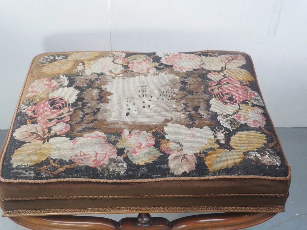 An antique Scottish Baronial X-frame stool crafted from carved wood with scrolled feet, turned finials, and a brown velvet seat with floral tapestry top. View III