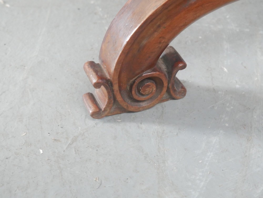 An antique Scottish Baronial X-frame stool crafted from carved wood with scrolled feet, turned finials, and a brown velvet seat with floral tapestry top. View IX