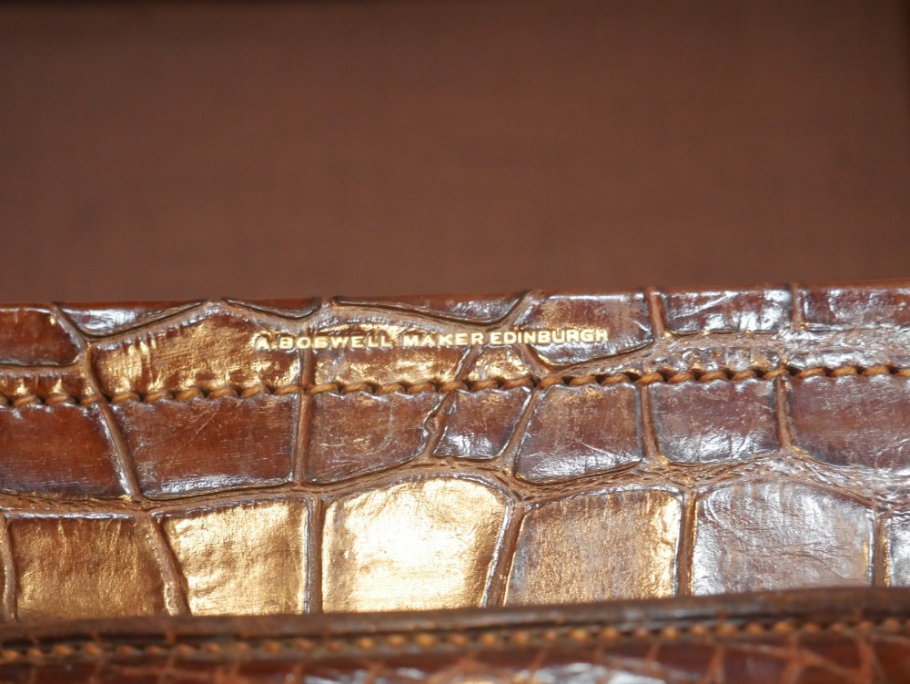 A small warm brown crocodile skin suitcase with brass locks and a stitched leather handle. View VIII