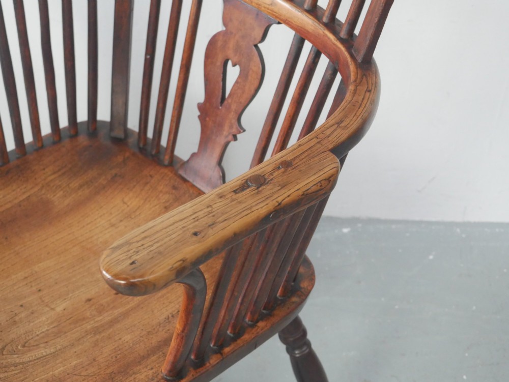 A warm brown antique Windsor armchair featuring a high back with a pierced wheelback splat, curved arms, and turned wooden legs. View II
