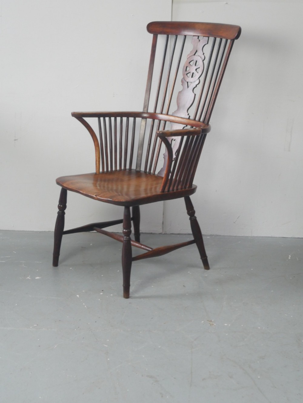 A warm brown antique Windsor armchair featuring a high back with a pierced wheelback splat, curved arms, and turned wooden legs. View III