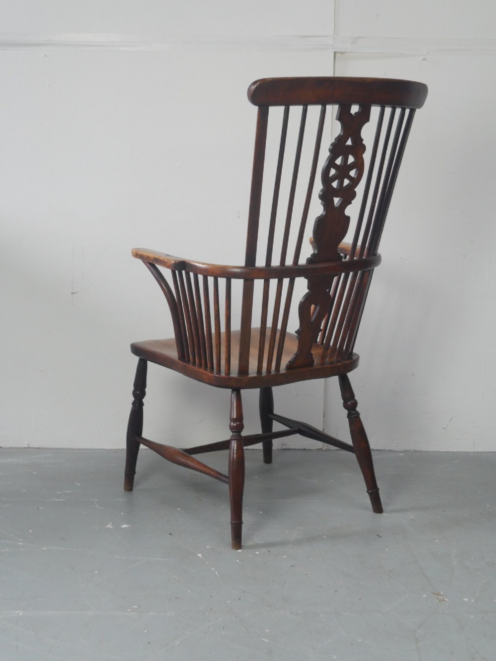 A warm brown antique Windsor armchair featuring a high back with a pierced wheelback splat, curved arms, and turned wooden legs. View IV