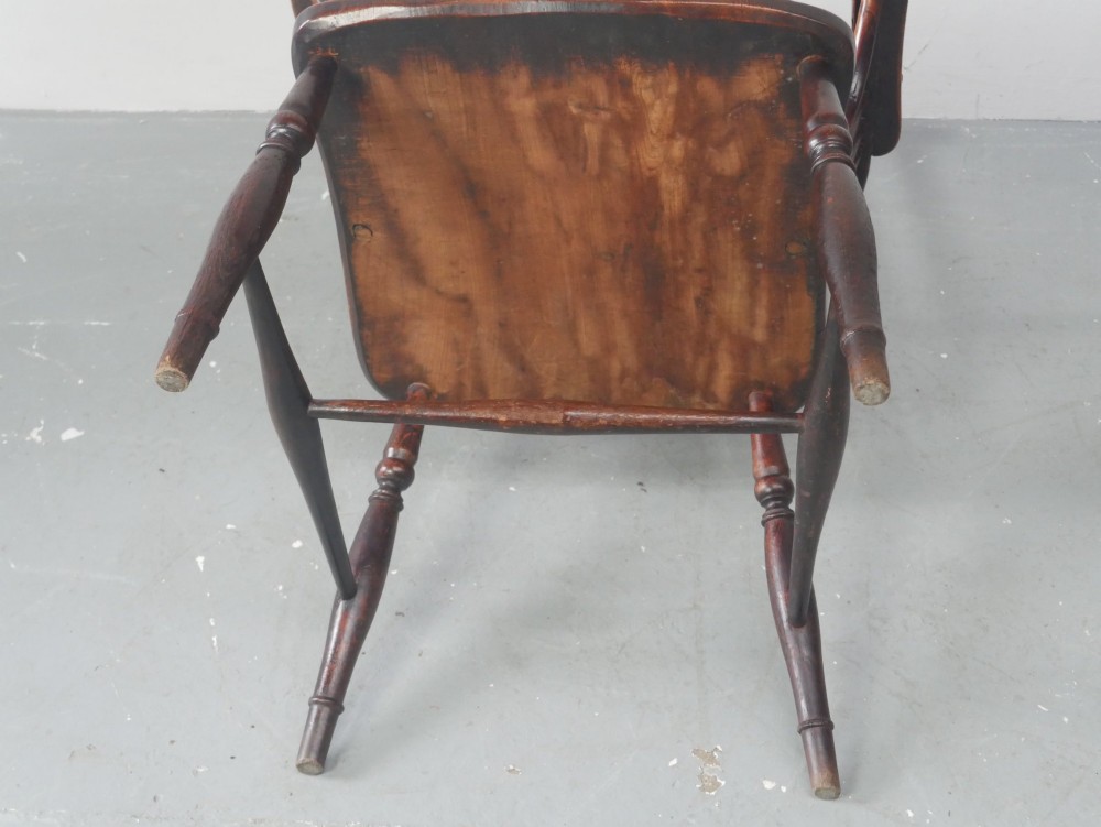 A warm brown antique Windsor armchair featuring a high back with a pierced wheelback splat, curved arms, and turned wooden legs. View VI