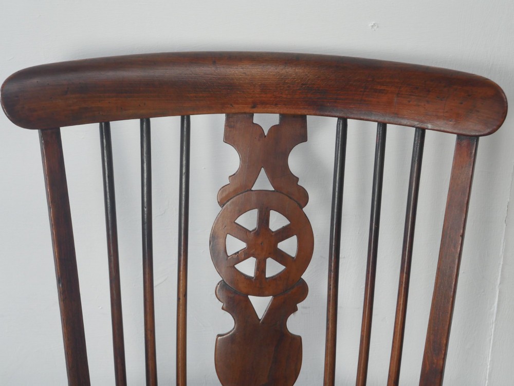 A warm brown antique Windsor armchair featuring a high back with a pierced wheelback splat, curved arms, and turned wooden legs. View VII