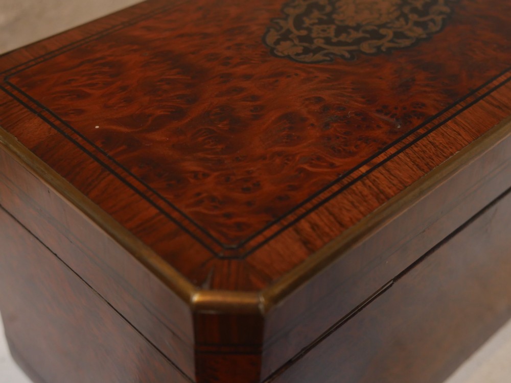 A 19th-century French amboyna wood box featuring canted corners, brass edging, and central brass inlay on the lid. View V
