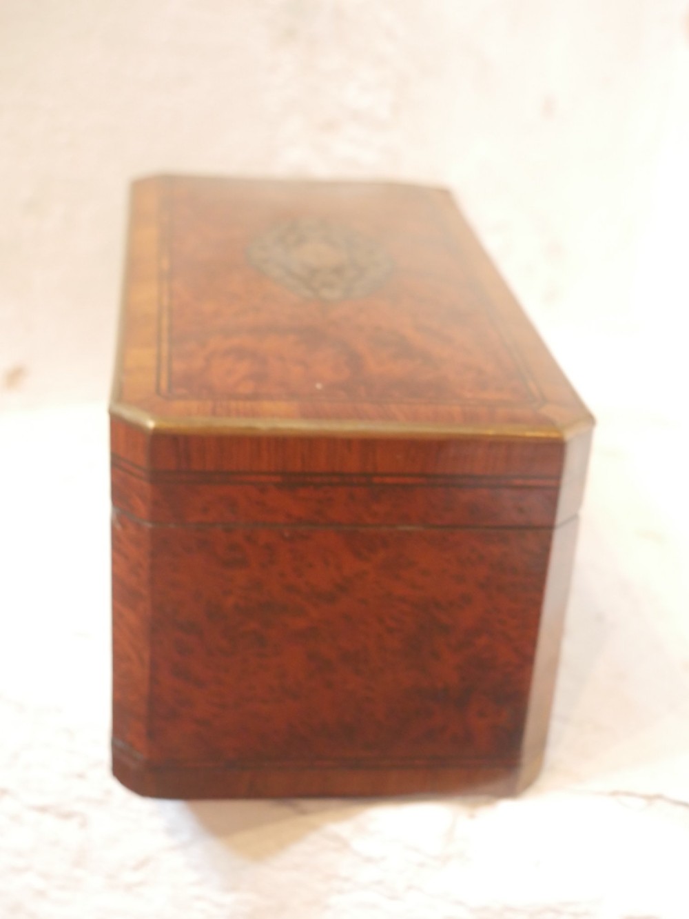 A 19th-century French amboyna wood box featuring canted corners, brass edging, and central brass inlay on the lid. View IX