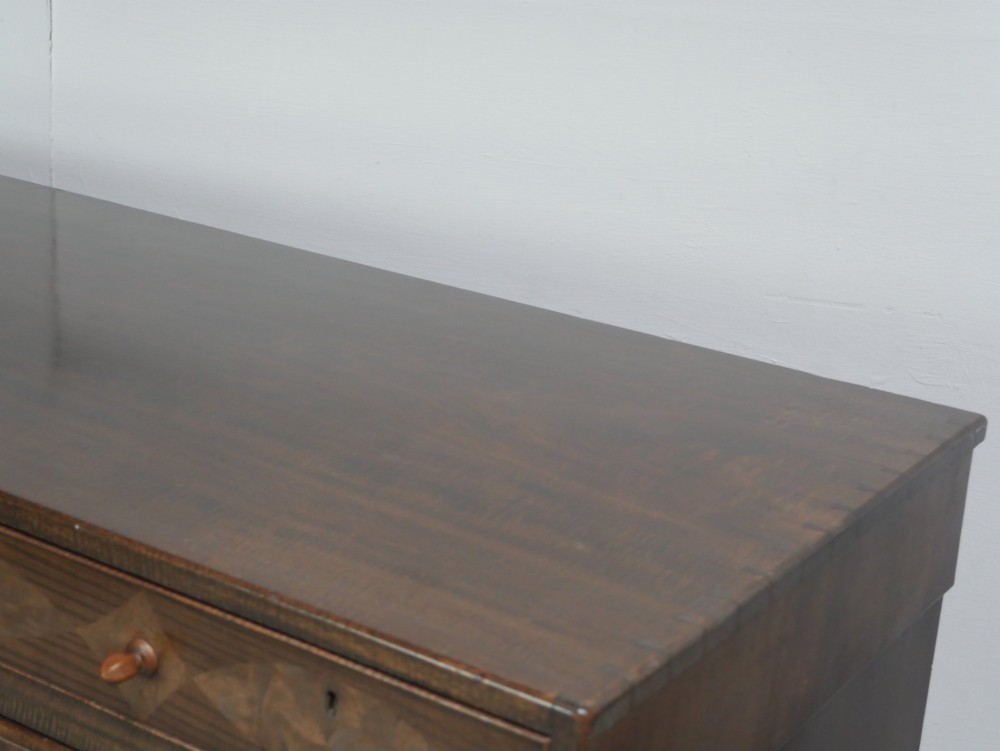 A wide Scottish flame mahogany chest of drawers featuring top diamond-inlaid frieze drawers, brass drop handles, and turned feet. View XI