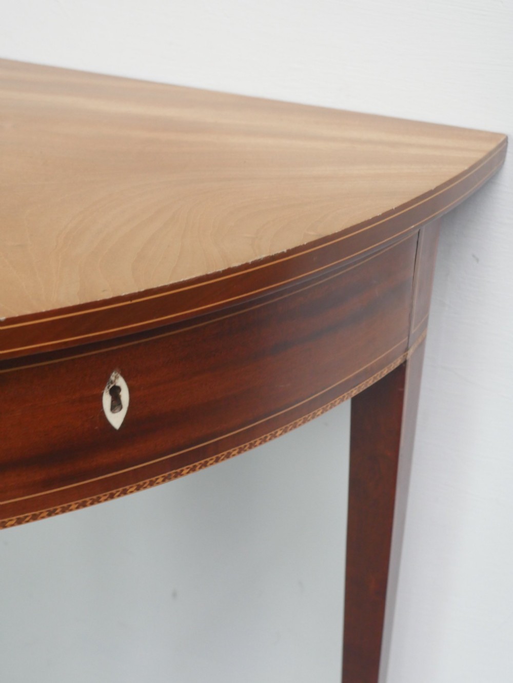A Regency mahogany demi-lune console table featuring satinwood stringing inlay, a central drawer, and four square tapered legs. View II