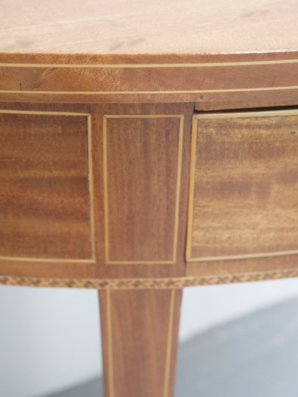 A Regency mahogany demi-lune console table featuring satinwood stringing inlay, a central drawer, and four square tapered legs. View IV