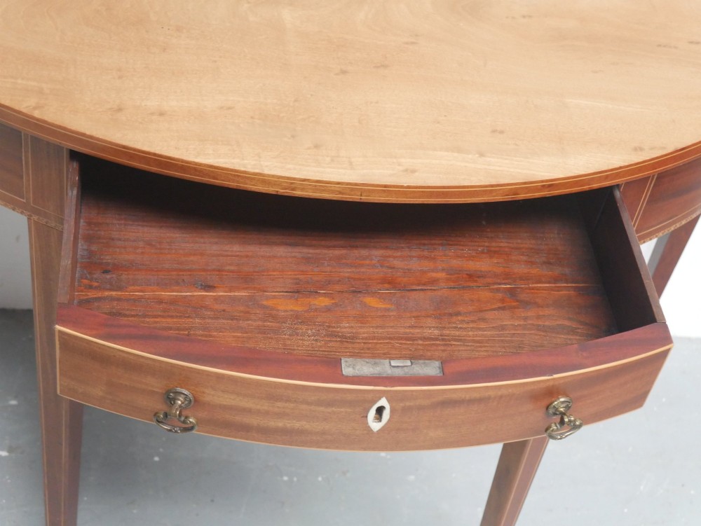 A Regency mahogany demi-lune console table featuring satinwood stringing inlay, a central drawer, and four square tapered legs. View V