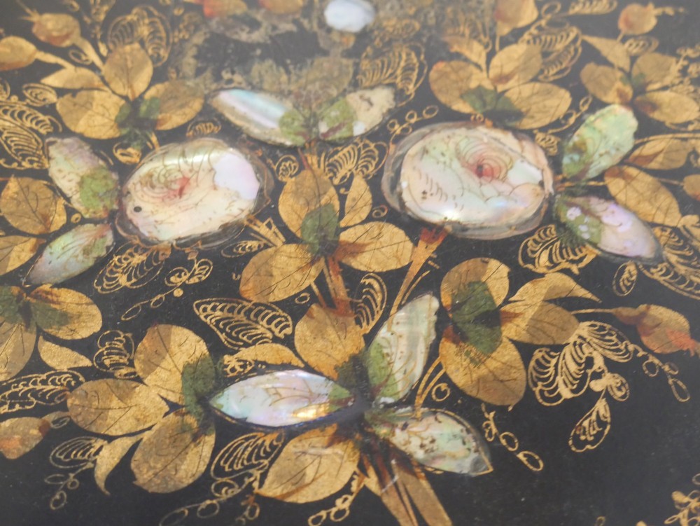 An oval black lacquered papier-mache tray decorated with gilt floral scrollwork and iridescent mother-of-pearl inlay. View VII