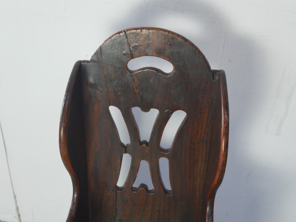 An 18th-century dark oak childs chair featuring a high winged back with decorative pierced cutouts and a solid box base. View IV
