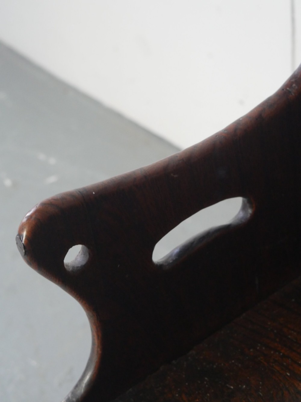 An 18th-century dark oak childs chair featuring a high winged back with decorative pierced cutouts and a solid box base. View VII