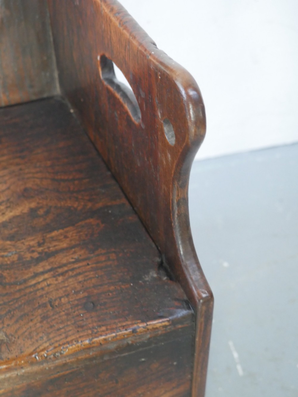 An 18th-century dark oak childs chair featuring a high winged back with decorative pierced cutouts and a solid box base. View VIII