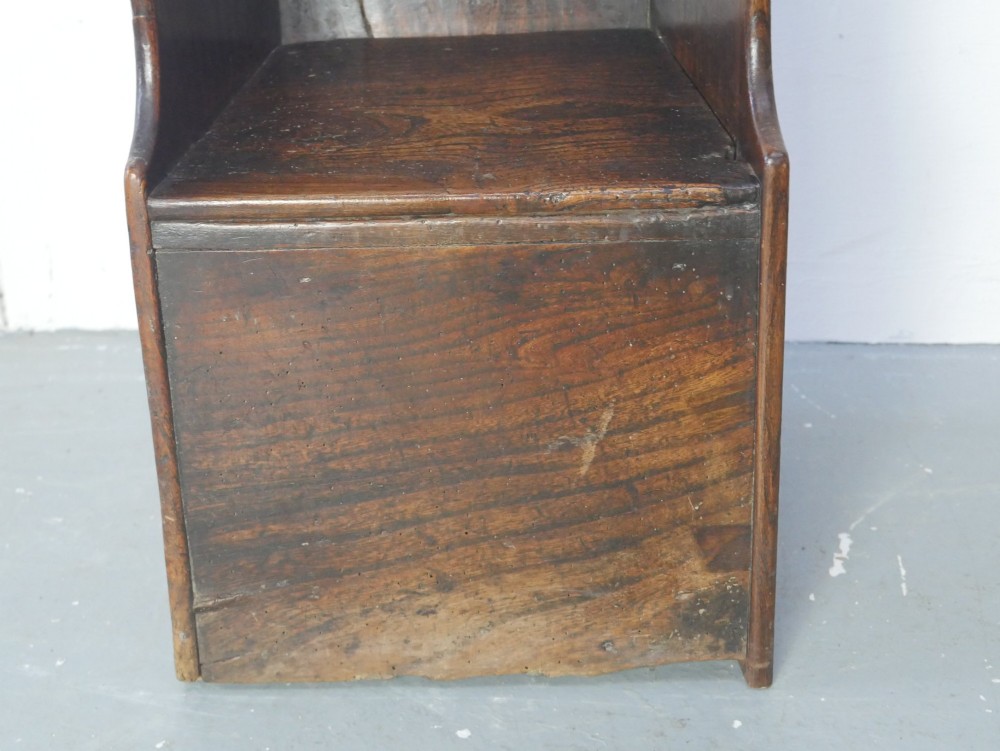 An 18th-century dark oak childs chair featuring a high winged back with decorative pierced cutouts and a solid box base. View IX