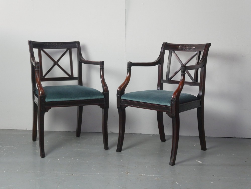 A pair of dark mahogany Regency Revival armchairs featuring cross-back splats, curved arms, and teal velvet upholstered seats.