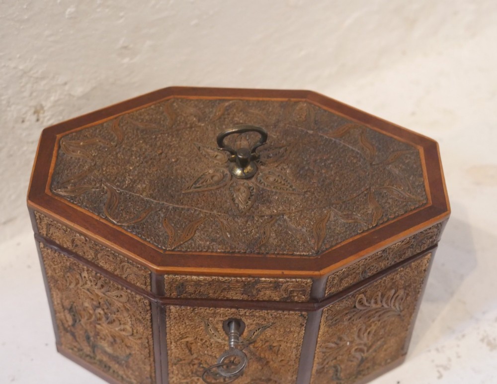 An 18th-century octagonal wooden tea caddy featuring intricate paper filigree quilling, foliate designs, a top brass loop handle, and a key. View II