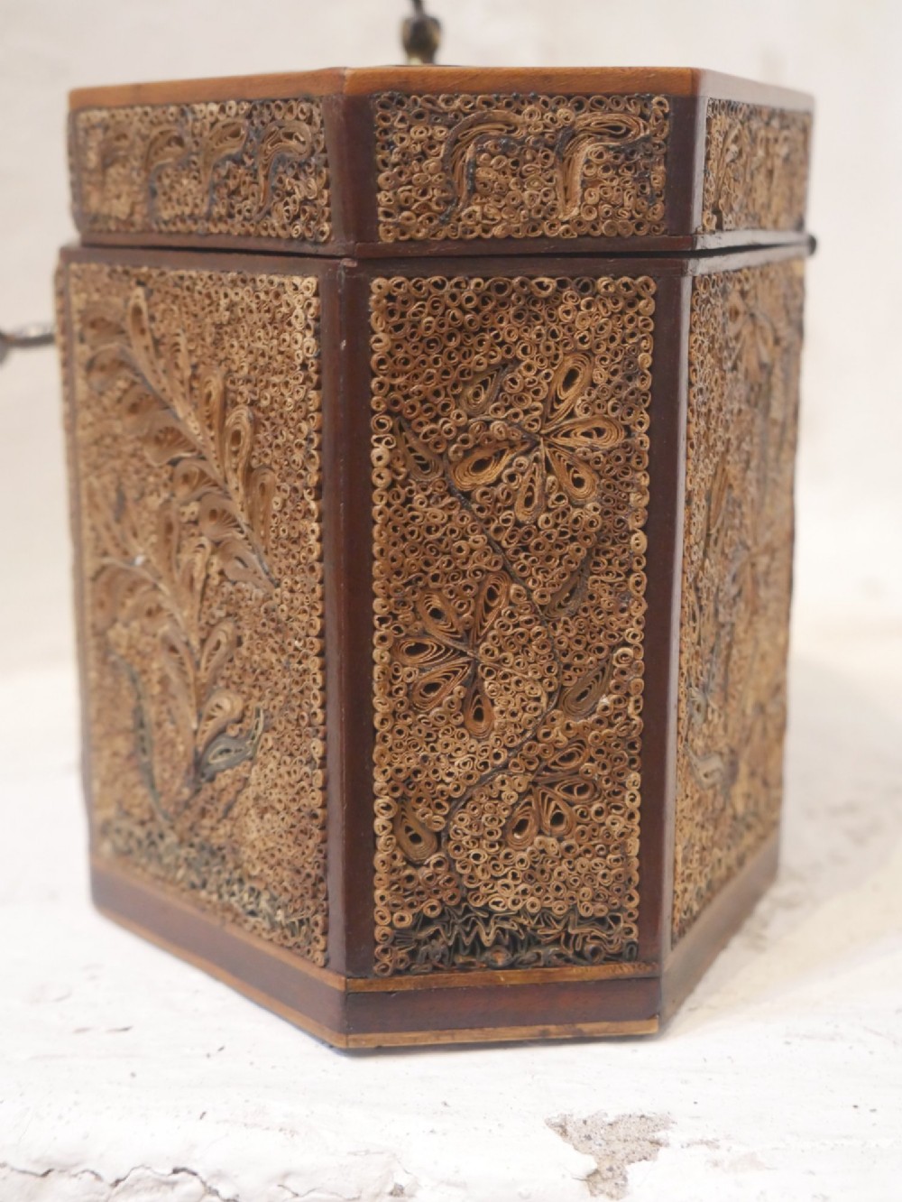 An 18th-century octagonal wooden tea caddy featuring intricate paper filigree quilling, foliate designs, a top brass loop handle, and a key. View IV