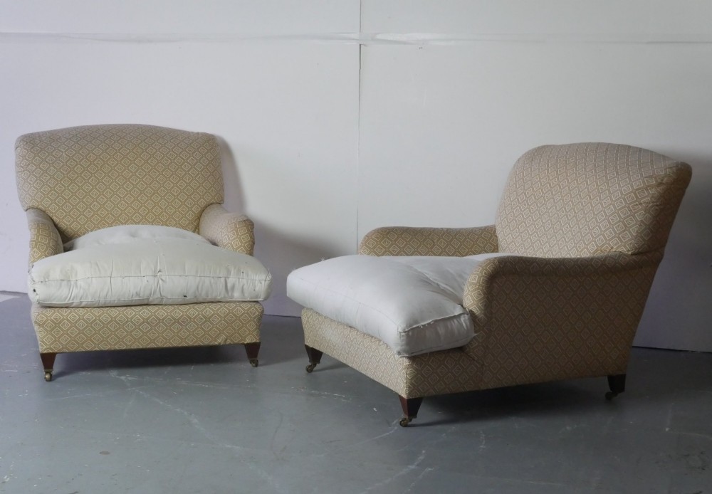 A pair of large upholstered armchairs in beige patterned fabric with deep white down cushions and brass castors on tapered timber feet. View II