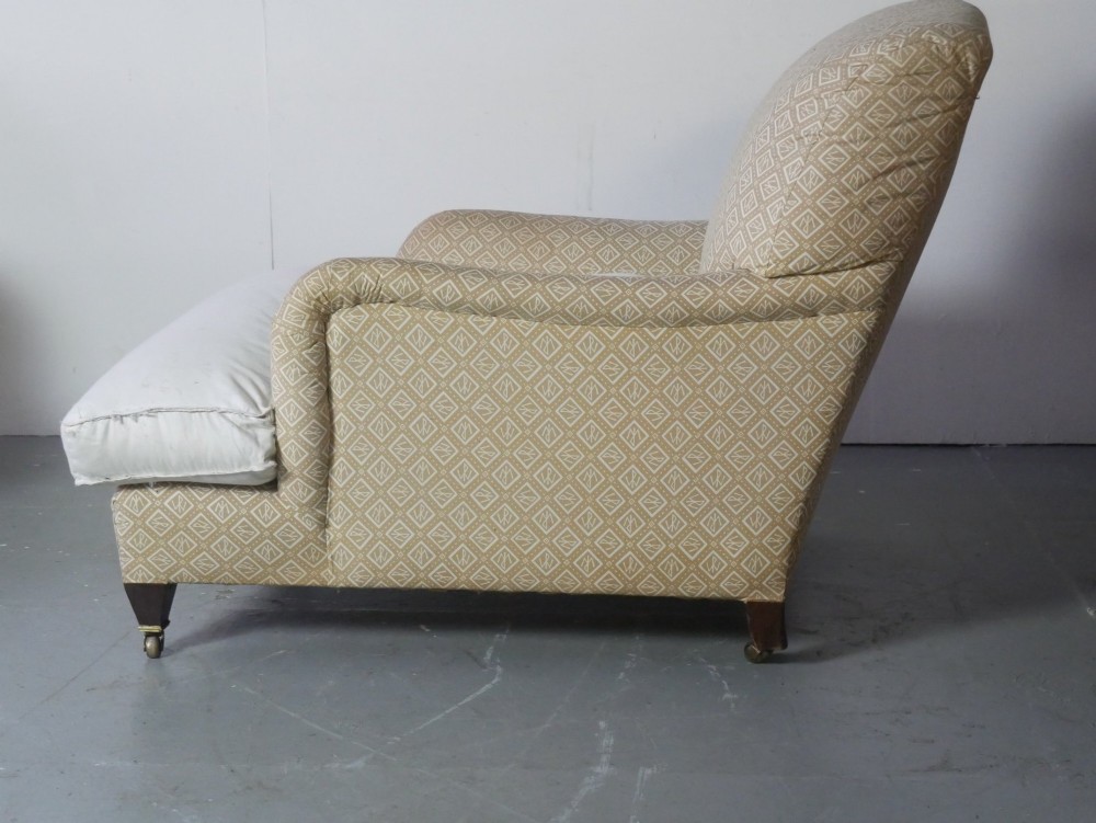 A pair of large upholstered armchairs in beige patterned fabric with deep white down cushions and brass castors on tapered timber feet. View III