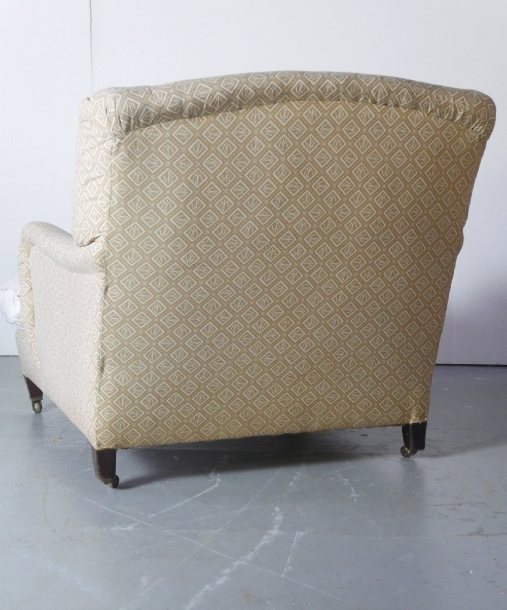 A pair of large upholstered armchairs in beige patterned fabric with deep white down cushions and brass castors on tapered timber feet. View IV